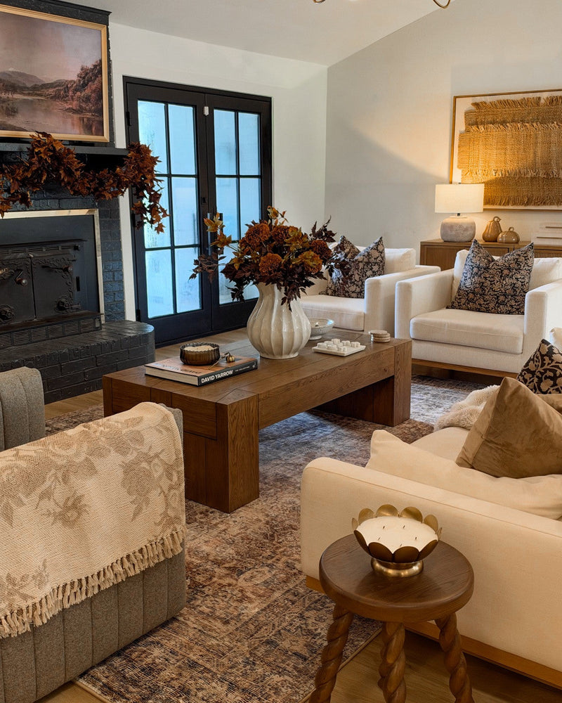 Living room with cream sofas and chairs, a wood coffee table and a faded vintage-style rug in warm browns and charcoal